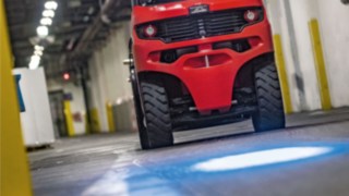 Linde counterbalanced forklift truck with BlueSpot projects a blue warning dot onto the warehouse floor