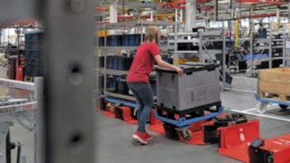 Operator loads a tugger train trailer with a half-size trolley