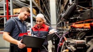 Two service technicians from Linde Material Handling are looking at a laptop next to a vehicle.