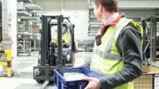 Employee walking in front of a forklift truck