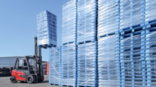 Thanks to its robust swing axle and long wheelbase, the X35 is ideal for outdoor use. Linde Material Handling X35 electric forklift truck stacking goods in outdoor use
