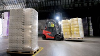 Linde forklift truck transporting goods in a dark hall with light