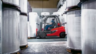 Linde forklift truck driving between rolls of paper