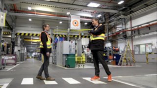 Two factory workers with the Linde Secure Distance Vest meet at a safe distance