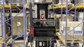 Driver in the cab of a narrow-aisle K truck from Linde Material Handling amongst high shelving