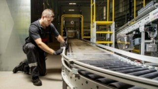 A service technician from Linde MH repairs a roller conveyor.
