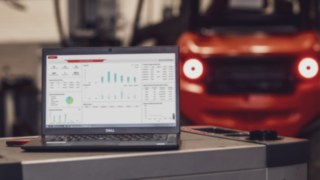 Fleet Dashboard of the Linde Warehouse Manager on a Laptop screen and a forklift truck in the background