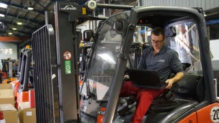 Technician is inspecting a used truck Technician with laptop inspection a truck for the preparation as an approved truck