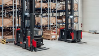 Two Linde MH very narrow aisle trucks with integrated personnel protection system in front of the narrow-aisle warehouse
