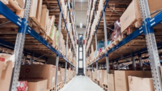 A very narrow aisle truck lifts a pallet in a high-bay warehouse surrounded by racks of boxes