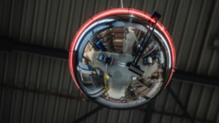 A round mirror with a light strip lit up red to indicate that a forklift truck is approaching. A round mirror with a light strip lit up red to indicate that a forklift truck is approaching.