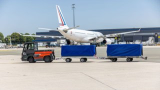 A Linde MH P250 tow tractor is transporting cargo.