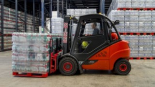 A hired V-forklift from Linde transports a pallet of water boxes from Agua Mineral in the warehouseLager