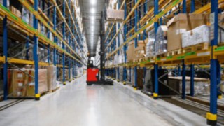 An R-MATIC driverless reach truck operating in a wide aisle at FIEGE.