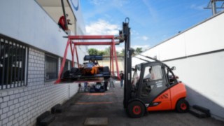 A Linde rental truck carefully transports a race car 