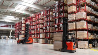 Linde very narrow-aisle truck and reach truck in front of a pallet rack