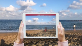 Industrial truck projected onto the surrounding beach using the Virtual Showroom app from Linde Material Handling The Virtual Showroom app from Linde Material Handling projects an industrial truck onto the surrounding beach on the tablet screen.
