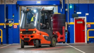 A warehouse worker at Michelin Tyre PLCE driving a Linde E20 forklift in reverse.