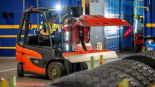 A Michelin Tyre PLC employee reaches for a stack of tires using a Linde E20 with a tire clamp.