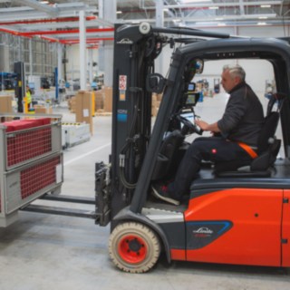A Linde electric forklift truck transports a mesh box