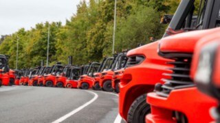 Many forklifts from Linde Material Handling lined up in a parking lot.